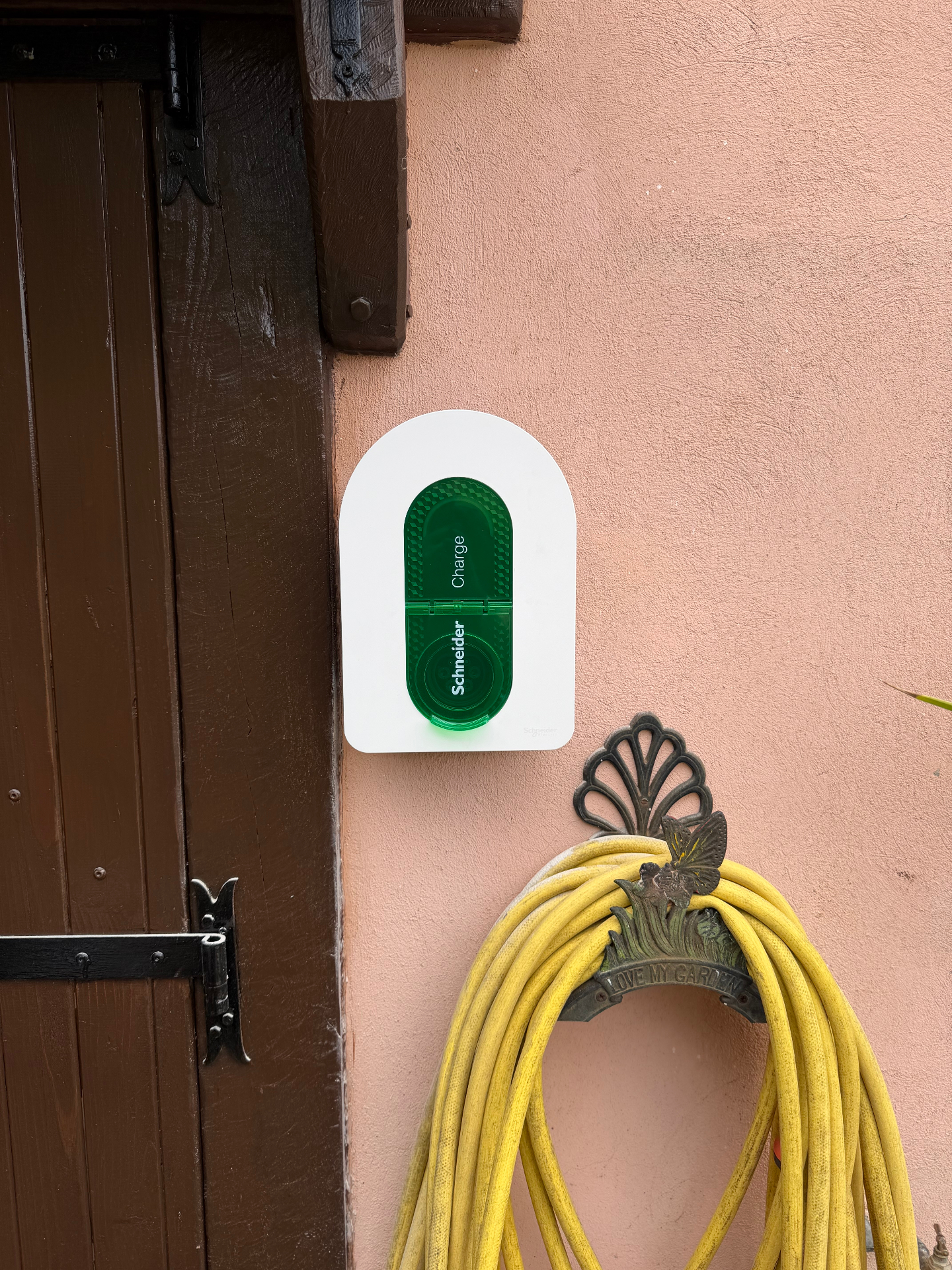 Borne Schneider Charge installée à côté d'un volet en bois sur façade saumon — installation Lumëel